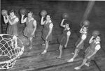 Women’s basketball team hold basketballs on court, circa 1940s-1960s by Clark University